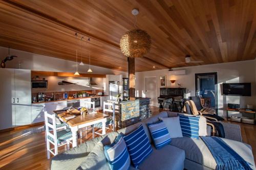 a living room with a blue couch and a kitchen at Adventure Bay Beach House in Adventure Bay