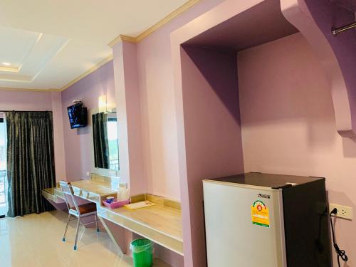a room with a table and a refrigerator in it at โรงแรมมาลินี in Surin