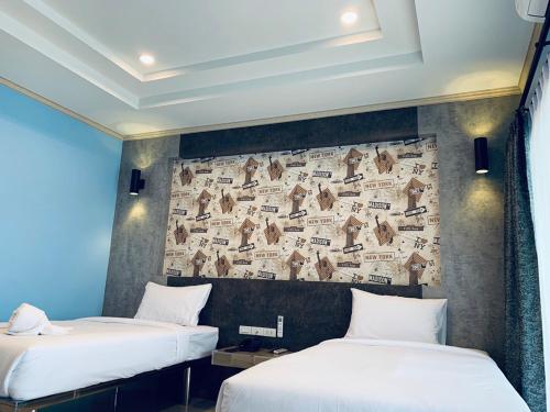 two beds in a room with a wall covered in newspaper at โรงแรมมาลินี in Surin