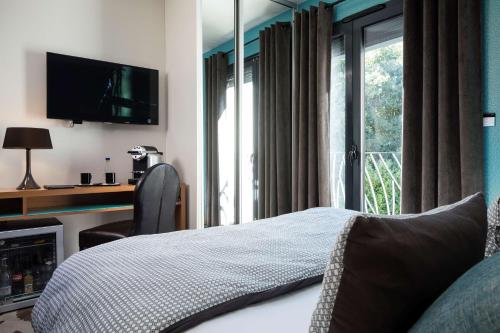 a bedroom with a bed and a tv and a window at Best Western Plus Hotel De La Regate-Erdre in Nantes
