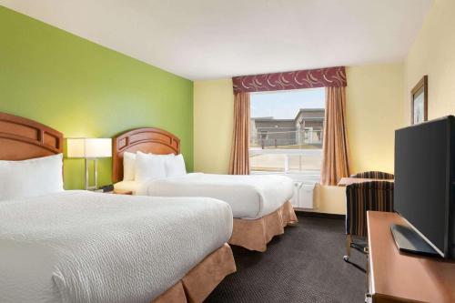 une chambre d'hôtel avec deux lits et une télévision à écran plat dans l'établissement Days Inn & Suites by Wyndham Thompson, à Thompson