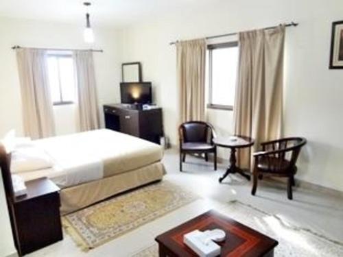 فندق دولفين في مسقط: غرفة نوم بسرير وطاولة وكراسي