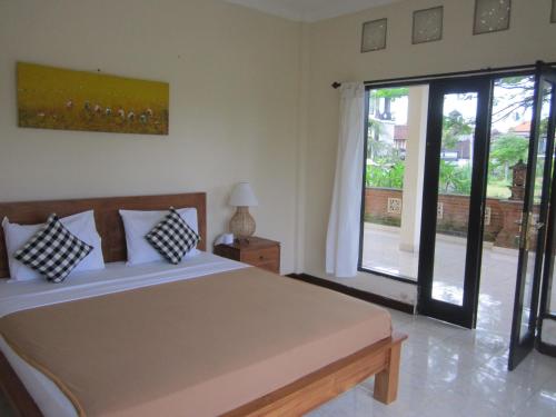 um quarto com uma cama grande e uma janela grande em Purnama di Bisma em Ubud