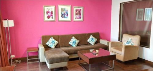 a living room with a couch and a pink wall at Royal Orchid Central, Pune in Pune