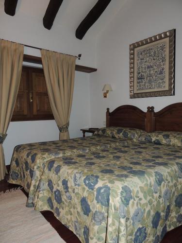 a bedroom with a bed with a comforter and curtains at Posada Maximo in Espinama