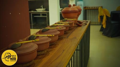 a row of clay pots sitting on a wooden counter at National Holiday Resort in Mahiyangana