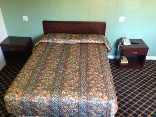 Una cama en una habitación con un teléfono en una mesa en Economy Inn, en Sun Valley