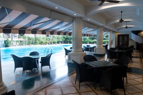a restaurant with tables and chairs and a swimming pool at The Classique Club in Mumbai