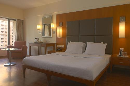 a hotel room with a large bed and a chair at The Classique Club in Mumbai