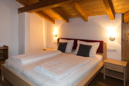 a large bed in a room with wooden ceilings at Apartments Haus Martin in Nova Levante