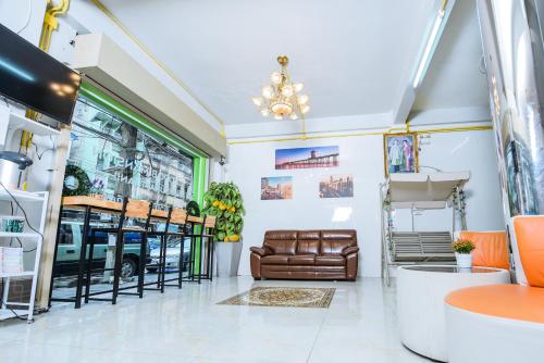 a salon with a leather couch and tables and chairs at Nadpob Mansion in Surat Thani