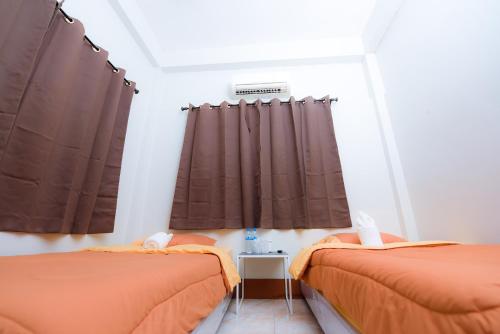 two beds in a room with brown curtains at Nadpob Mansion in Surat Thani