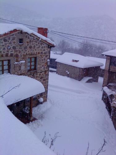 a house covered in snow next to a building at Casa Fidela in Lomeña