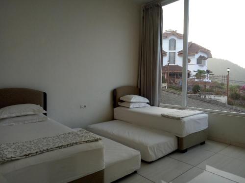two beds in a room with a large window at Villa batu malang panderman hill in Batu