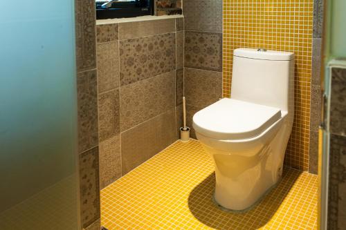 a bathroom with a toilet and a yellow tile floor at ChingTing B&B in Chishang