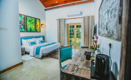 1 dormitorio con cama, escritorio y mesa en Simpson's Forest Hotel, en Kandy