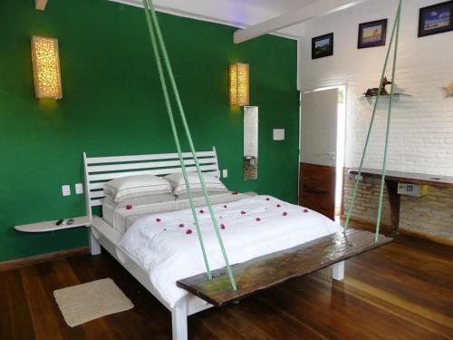 a bedroom with a swinging bed in a green wall at Pousada O Refúgio in Jericoacoara