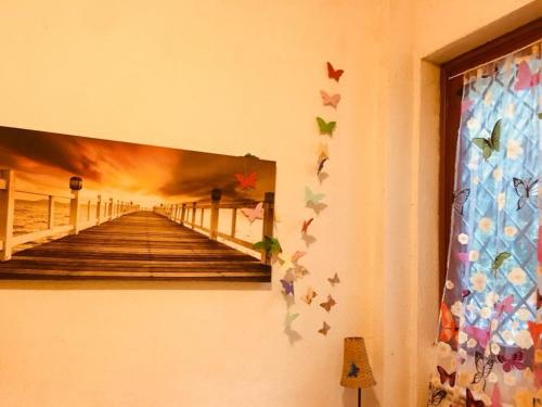 a painting of a pier with butterflies on a wall at La casa di Nataly in Fregene