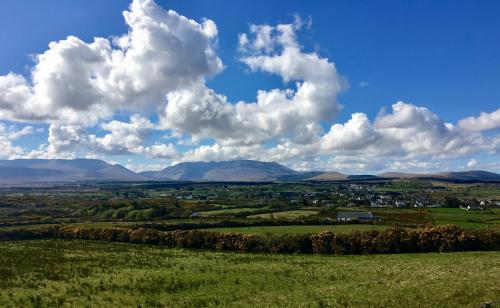 a view of a green field with mountains in the background at The Garden Room at Sleepy Hollow in Louisburgh