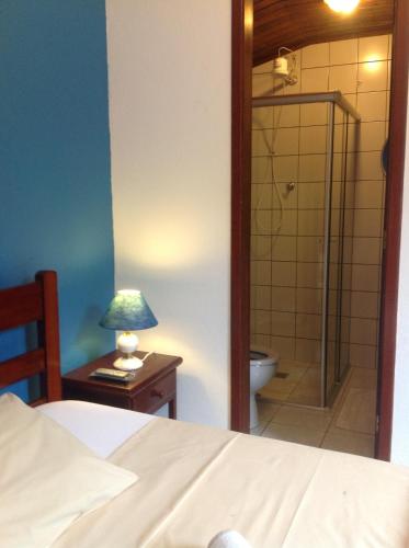 a bedroom with a bed and a bathroom with a shower at Pousada Telhado Azul in Abraão