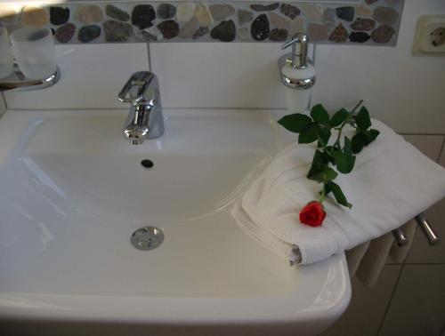 - un lavabo blanc avec une serviette et une fleur dans l'établissement Gästehaus Alt Mehring, à Mehring