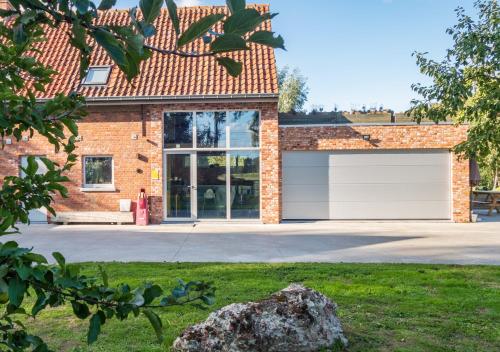 een stenen huis met twee garagedeuren in een tuin bij De Vakantieschuur in Sint-Laureins