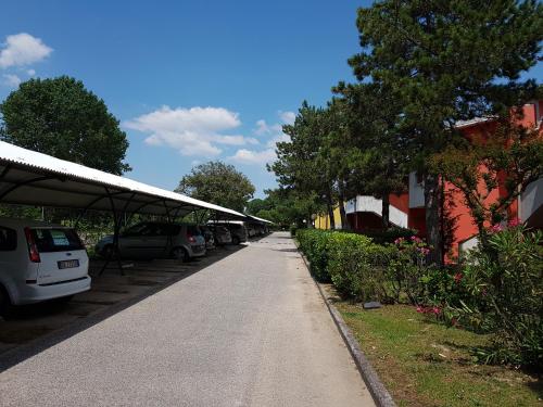 a sidewalk with cars parked in a parking lot at Adriella apartments in Bibione