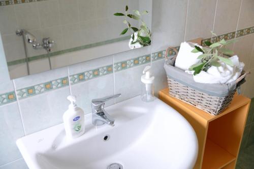 a bathroom sink with a mirror and a basket of towels at "La casa di Mariagrazia" Appartamento 4 locali in Sammichele di Bari
