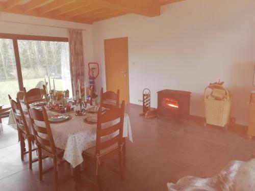 a dining room with a table and a fireplace at Florennes Gîte neuf 150 M2 devant un grand lac privé de 2 hectares poissonneux au milieu des bois in Florennes