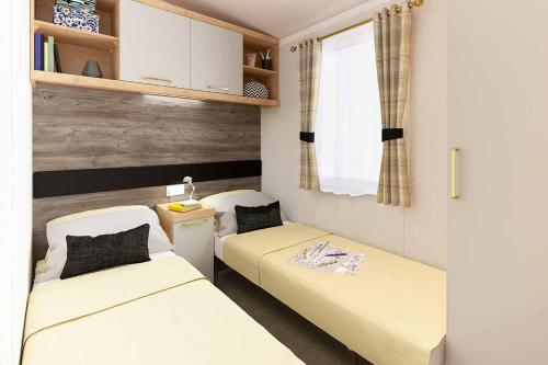 サンダースフットにあるSunnyglen Holiday Parkのベッド2台と窓が備わる小さな客室です。