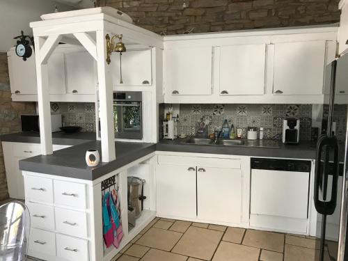 a white kitchen with white cabinets and a sink at Barsy 34 in Havelange
