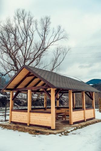 a wooden pavilion with a black roof in the snow at Вілла Софі in Verkhovyna