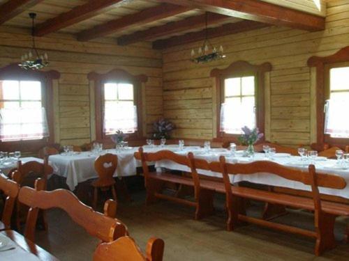 una sala da pranzo con tavoli e sedie bianchi e finestre di Őrszem Fogadó a Szalafő