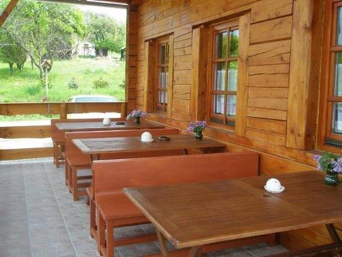a restaurant with wooden tables and benches and windows at Őrszem Fogadó in Szalafő