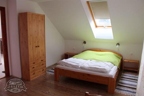 a bedroom with a bed and a wooden cabinet at Őrszem Fogadó in Szalafő