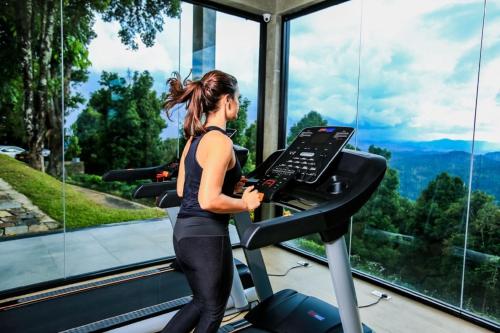 a woman running on a treadmill in a gym at Simpson's Forest - Luxury Boutique Resort & Spa - Kandy in Kandy