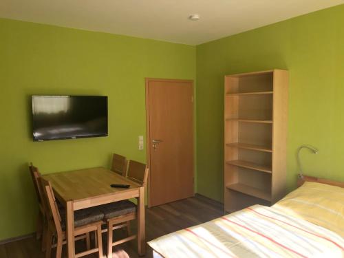 Zimmer mit einem Schreibtisch und einem Bett sowie einem Zimmer mit grünen Wänden in der Unterkunft Ferienwohnung Mayer in Rangsdorf