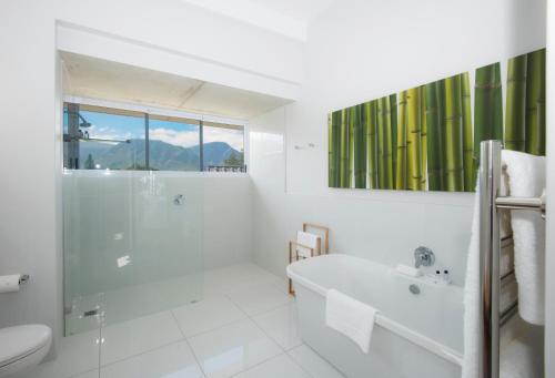 a white bathroom with a tub and a sink at Bamboo Guest House in Hermanus