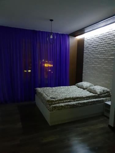 a bedroom with a bed and a purple curtain at Travel station apartment in Ivano-Frankivsʼk