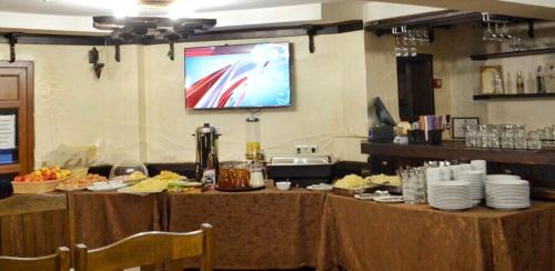 Una habitación con mesas con comida y un televisor en la pared. en Hotel Marilen, en Bukovel