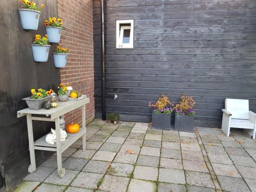 a patio with flowers and plants in pots on a wall at B&B Usselo Klein, fijn en uniek! in Enschede