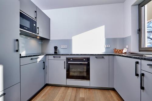 a kitchen with white cabinets and a window at City Suites Murnau in Murnau am Staffelsee