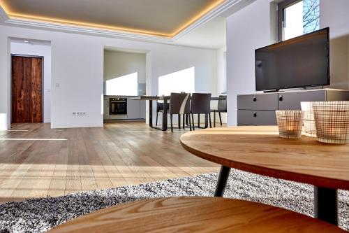 a living room with a table and a flat screen tv at City Suites Murnau in Murnau am Staffelsee