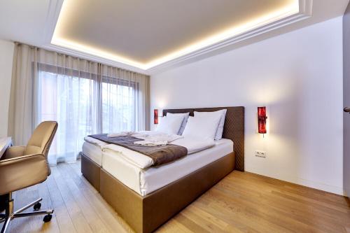 a bedroom with a bed and a chair and a window at City Suites Murnau in Murnau am Staffelsee
