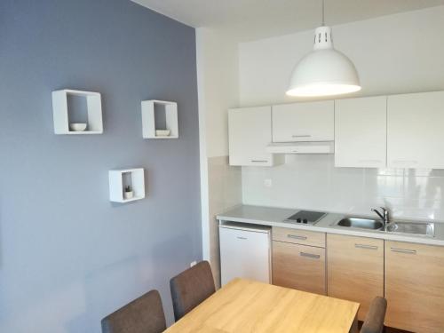 uma cozinha com armários brancos e uma mesa de madeira em Apartments Granzola em Sukošan
