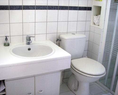 a white bathroom with a toilet and a sink at B&B Waterland in Middelie