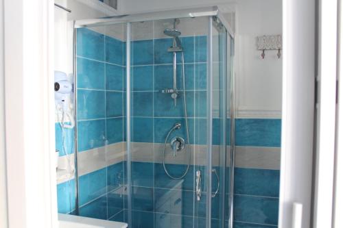 y baño con ducha de azulejos azules. en B&B AcquaDolce, en Cala Gonone