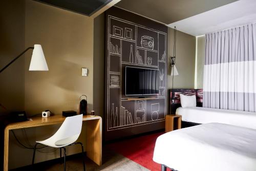 una camera d'albergo con letto, scrivania e TV di Ibis Milano Centro a Milano