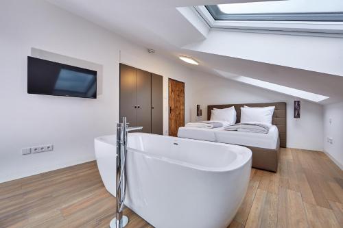a bathroom with a bath tub and two beds at City Suites Murnau in Murnau am Staffelsee