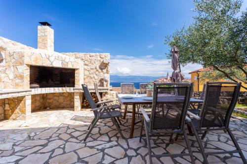 a patio with a table and chairs and a stone fireplace at Villa Pinia in Vrbnik